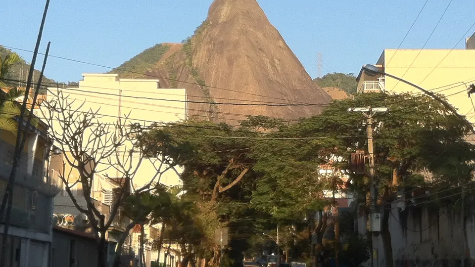 Rua arborizada no Grajaú com o morro do Parque do Grajaú ao fundo